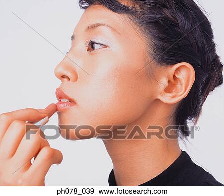 Young woman applying lipstick View Large Photo Image Stock Photo - Young woman applying lipstick. Fotosearch