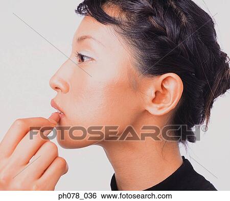 Young woman applying lipstick View Large Photo Image Stock Photograph - Young woman applying lipstick. Fotosearch
