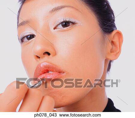 Young woman applying lipstick with a lip brush View Large Photo Image Stock Image - Young woman applying lipstick with a lip brush. Fotosearch