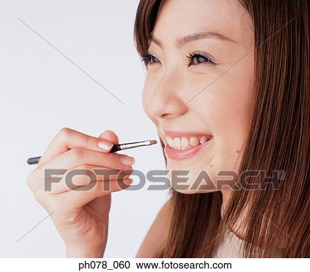 Young woman applying lipstick with a lip brush View Large Photo Image Stock Image - Young woman applying lipstick with a lip brush. Fotosearch