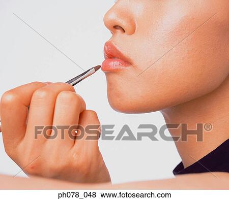 Young woman applying lipstick with a lip brush View Large Photo Image Stock Photo - Young woman applying lipstick with a lip brush. Fotosearch