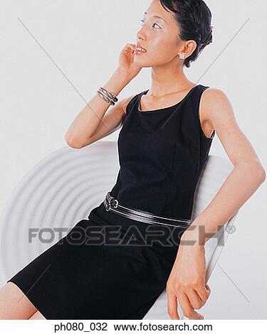 Stock Image - Portrait of a young woman sitting, Confident pose. Fotosearch
