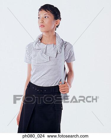 Picture - Young woman carrying handbag, hand on hip. Fotosearch
