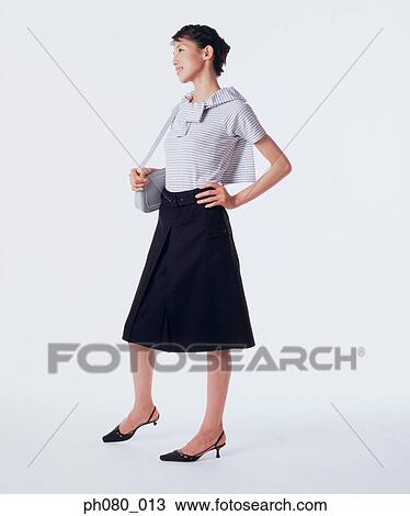Stock Image - Young woman carrying handbag, hand on hip . Fotosearch