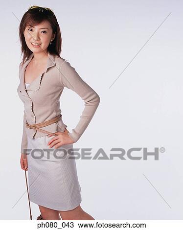 Stock Image - Young woman carrying handbag, hand on hip. Fotosearch