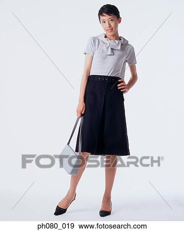 Stock Photo - Young woman carrying handbag, hand on hip. Fotosearch