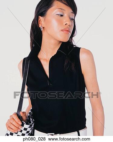 Stock Photo - Young woman carrying handbag, posing. Fotosearch