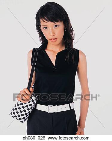 Stock Photograph - Young woman carrying handbag, posing. Fotosearch
