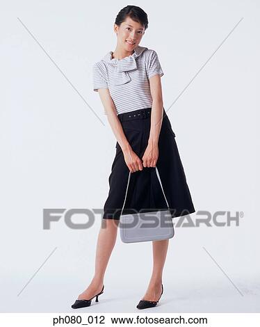Young woman holding handbag, posing View Large Photo Image Stock Image - Young woman holding handbag, posing. Fotosearch