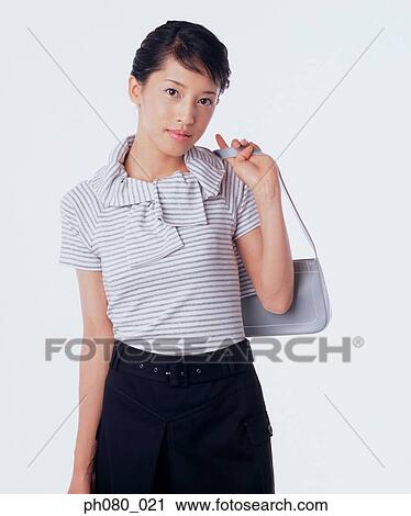 Young woman holding handbag, posing View Large Photo Image Stock Image - Young woman holding handbag, posing. Fotosearch