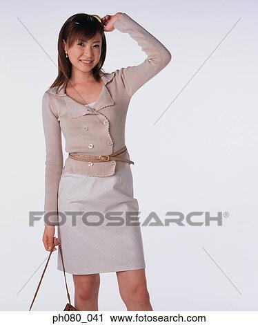 Stock Image - Young woman holding handbag, posing. Fotosearch