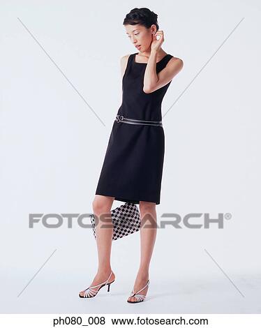 Young woman holding handbag, posing View Large Photo Image Stock Photo - Young woman holding handbag, posing. Fotosearch