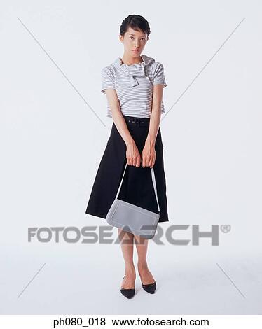 Stock Photo - Young woman holding handbag, posing. Fotosearch
