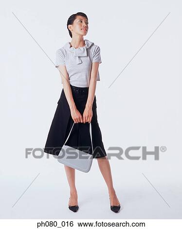 Young woman holding handbag, posing View Large Photo Image Stock Photograph - Young woman holding handbag, posing. Fotosearch