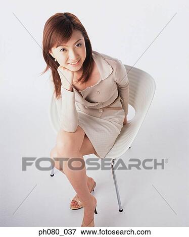 Young woman sitting, resting chin on hand, smiling View Large Photo Image Stock Photo - Young woman sitting, resting chin on hand, smiling . Fotosearch