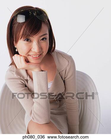 Young woman sitting, resting chin on hand, smiling View Large Photo Image Stock Photograph - Young woman sitting, resting chin on hand, smiling . Fotosearch