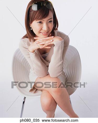 Young woman sitting, resting chin on hand, smiling View Large Photo Image Stock Photography - Young woman sitting, resting chin on hand, smiling . Fotosearch