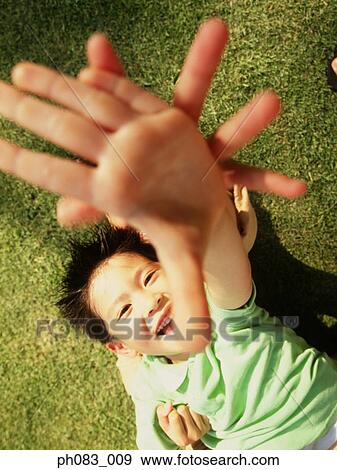 Stock Photo - Brother and sister lying on grass, arms stretched. Fotosearch
