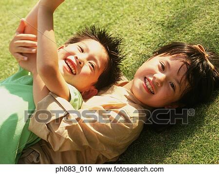 Brother and sister lying on grass, smiling View Large Photo Image Stock Image - Brother and sister lying on grass, smiling. Fotosearch