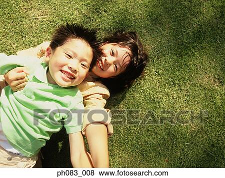 Brother and sister lying on grass, smiling View Large Photo Image Stock Photo - Brother and sister lying on grass, smiling. Fotosearch