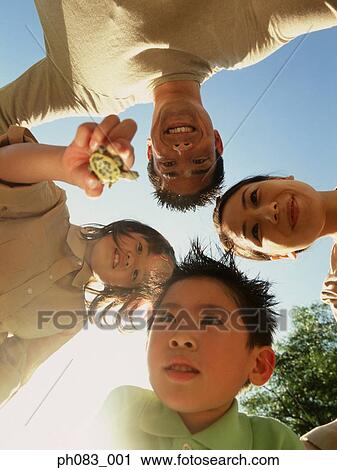 Stock Image - Family of four standing in circle, daughter holding terrapin, underneath view . Fotosearch