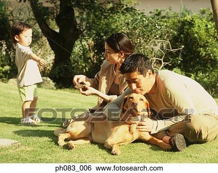 Stock Photograph - Family sitting in a park with pet dog. Fotosearch