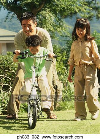Father teaching young son to ride bicycle View Large Photo Image Stock Image - Father teaching young son to ride bicycle . Fotosearch