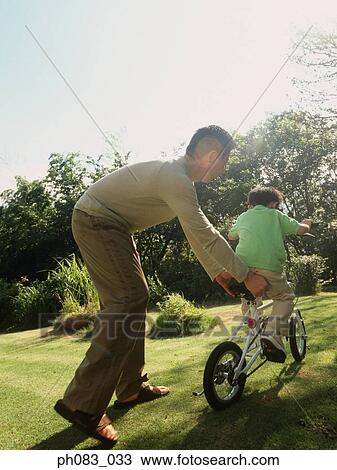 Father teaching young son to ride bicycle View Large Photo Image Stock Image - Father teaching young son to ride bicycle . Fotosearch