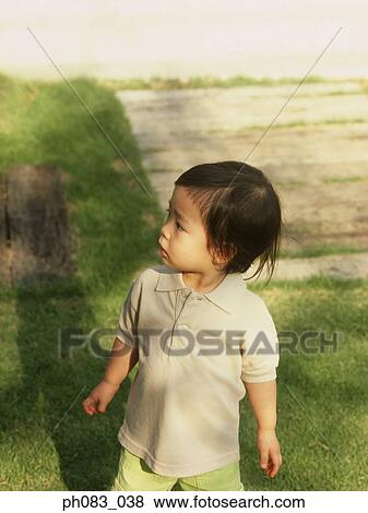 Young boy standing in backyard, looking away View Large Photo Image Stock Photo - Young boy standing in backyard, looking away. Fotosearch