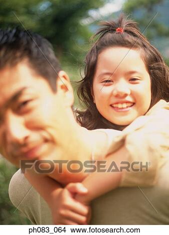 Picture - Young daughter having a piggyback from her father. Fotosearch
