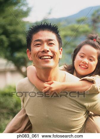 Stock Image - Young daughter having a piggyback from her father. Fotosearch