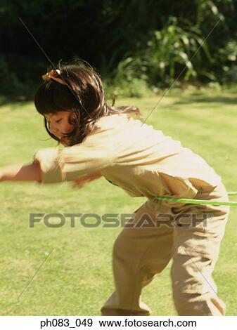 Stock Photo - Young girl playing with hula hoop. Fotosearch
