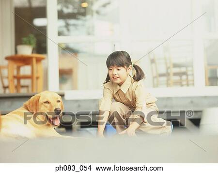 Picture - Young girl playing with pet dog. Fotosearch