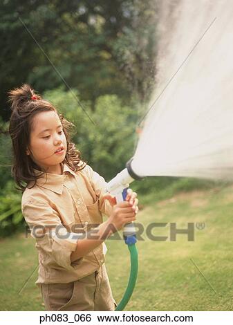 Young girl spraying water with hose View Large Photo Image Stock Photograph - Young girl spraying water with hose. Fotosearch