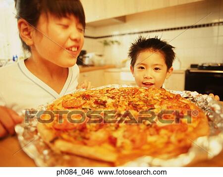 Boy and girl smiling, pizza in foreground View Large Photo Image Stock Photograph - Boy and girl smiling, pizza in foreground. Fotosearch