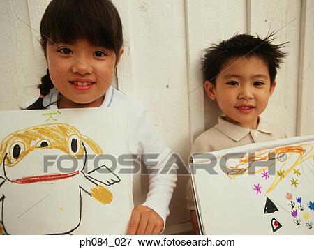 Stock Photo - Brother and sister showing off their drawings. Fotosearch