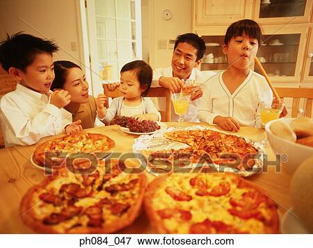 Stock Photo - Family dining, table full of pizza. Fotosearch