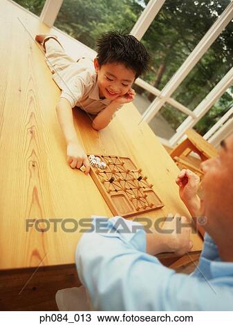 Stock Image - Father and son playing board game. Fotosearch