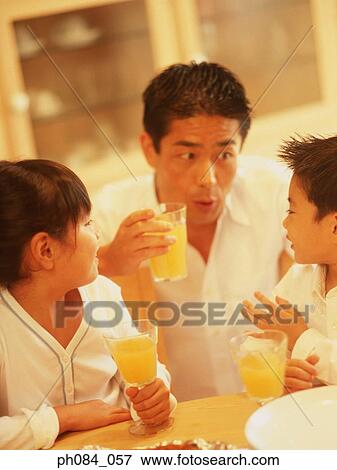 Stock Photo - Father and son talking. Hands holding glasses of orange juice. Fotosearch