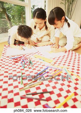 Stock Photograph - Mother and children drawing using color pencils. Fotosearch