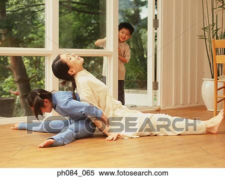 Stock Photography - Mother and daughter back to back, son watching. Fotosearch