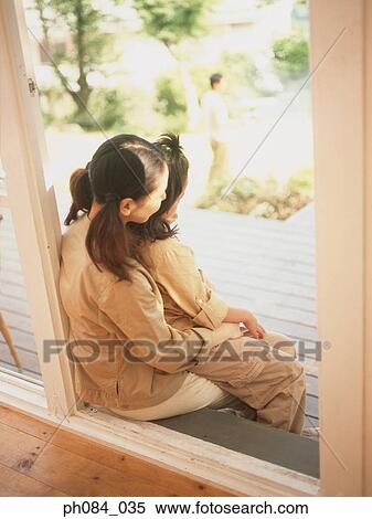 Stock Photography - Mother and daughter sitting on door step. Fotosearch