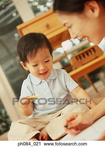 Stock Image - Mother and son drawing using crayon. Fotosearch