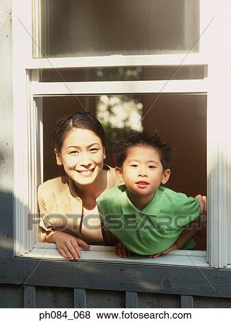 Stock Photo - Mother and son leaning out of window, smiling. Fotosearch
