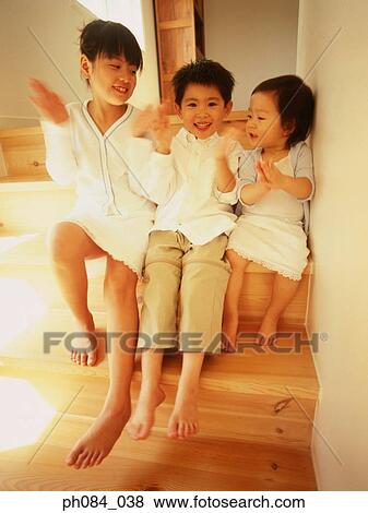 Stock Photo - Portrait of brothers and sister clapping hands. Fotosearch