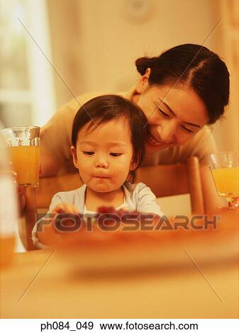 Young boy eating, mother watching over him View Large Photo Image Stock Photo - Young boy eating, mother watching over him. Fotosearch