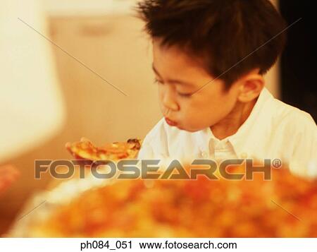 Stock Image - Young boy eating slice of pizza . Fotosearch