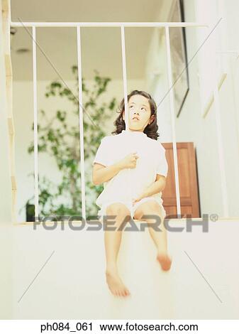 Stock Image - Young girl sitting on balcony, thinking. Fotosearch