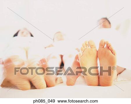Family lying on bed together View Large Photo Image Stock Photo - Family lying on bed together. Fotosearch
