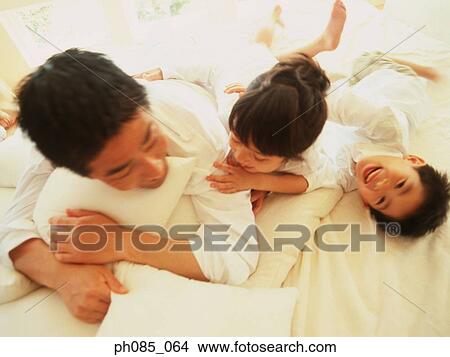 Father and children lying on bed View Large Photo Image Picture - Father and children lying on bed. Fotosearch